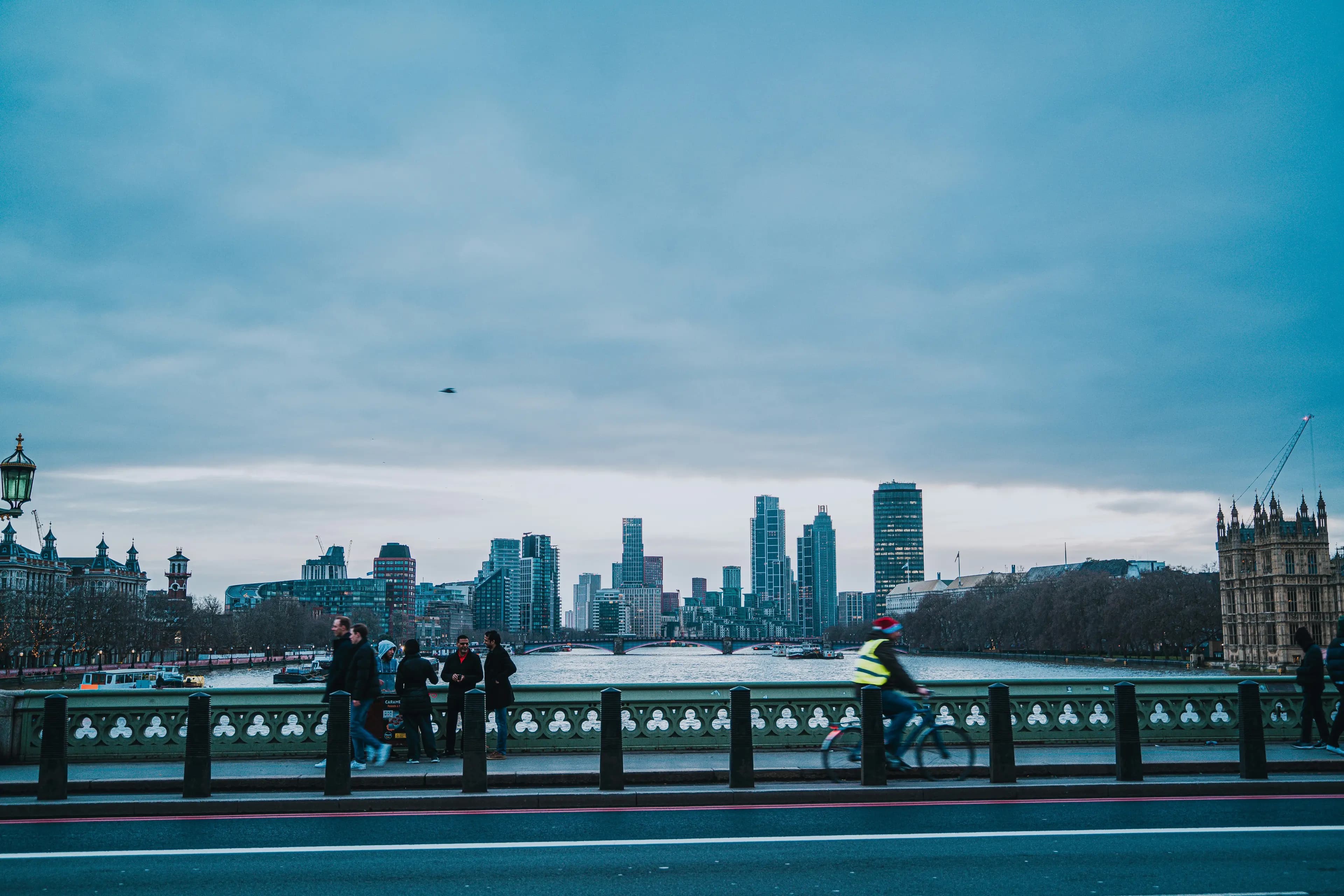 The view along the Thames from Westminster Bridge, with people walking and a cyclist passing